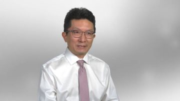 Dr. Chang seated wearing a white buttondown shirt and pink tie