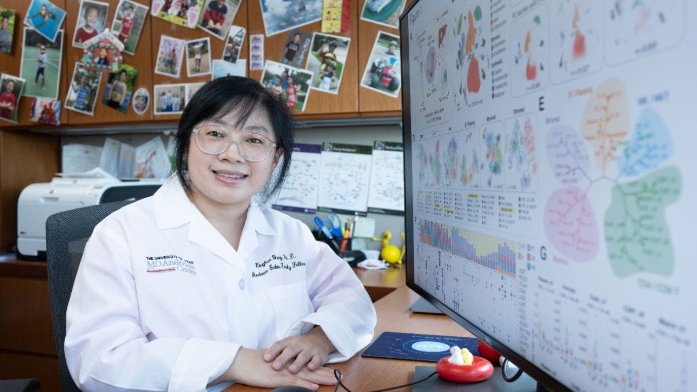 Photo of Linghua Wang, M.D., Ph.D. sitting at her computer