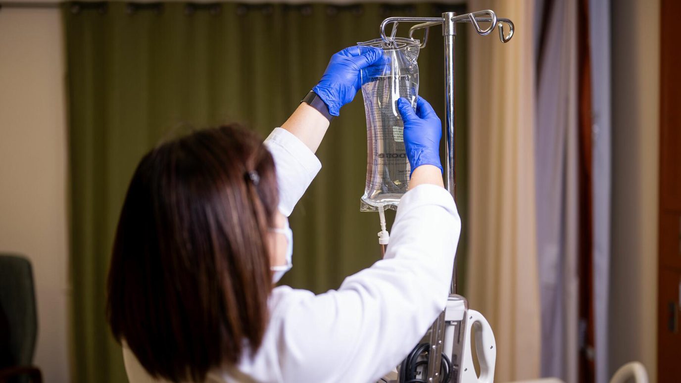 Image of nurse with IV pole in clinical trials