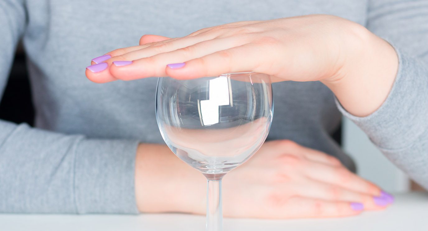 Close-up of woman's hand covering a wine class to reject alcohol