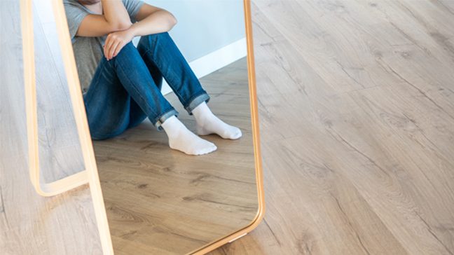 Unidentified woman sits facing a mirror