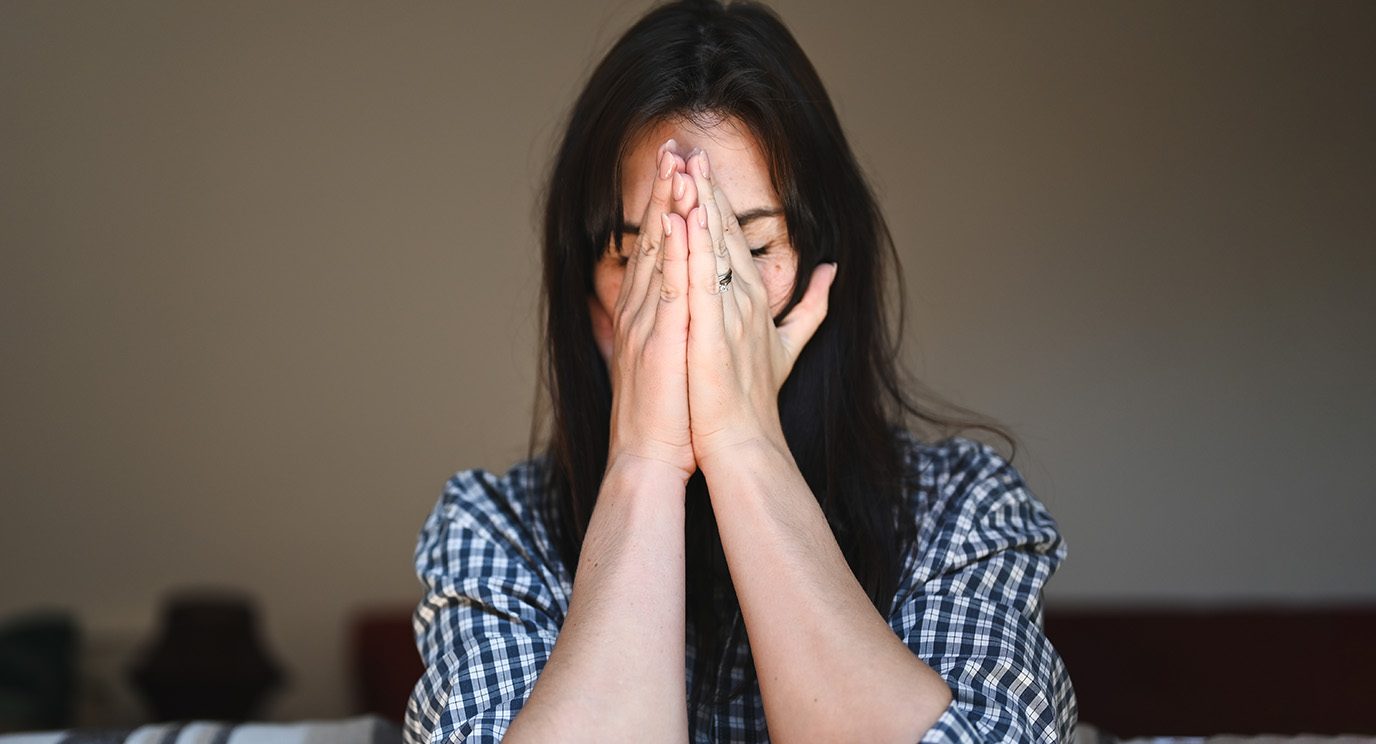 Visibly upset unidentifiable woman with hands over her face in distress