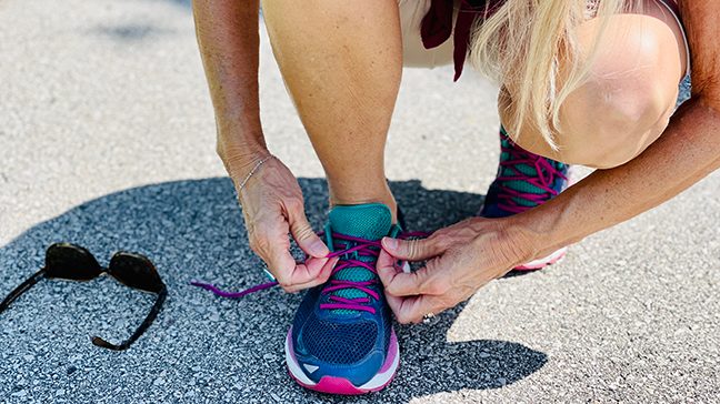 jogger kneels down to tie her shoelace, best workout routines for beginners