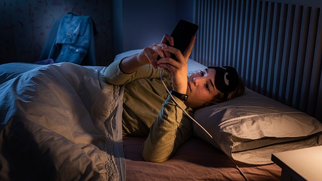 woman looking at her phone in bed, blue light filter and sleep