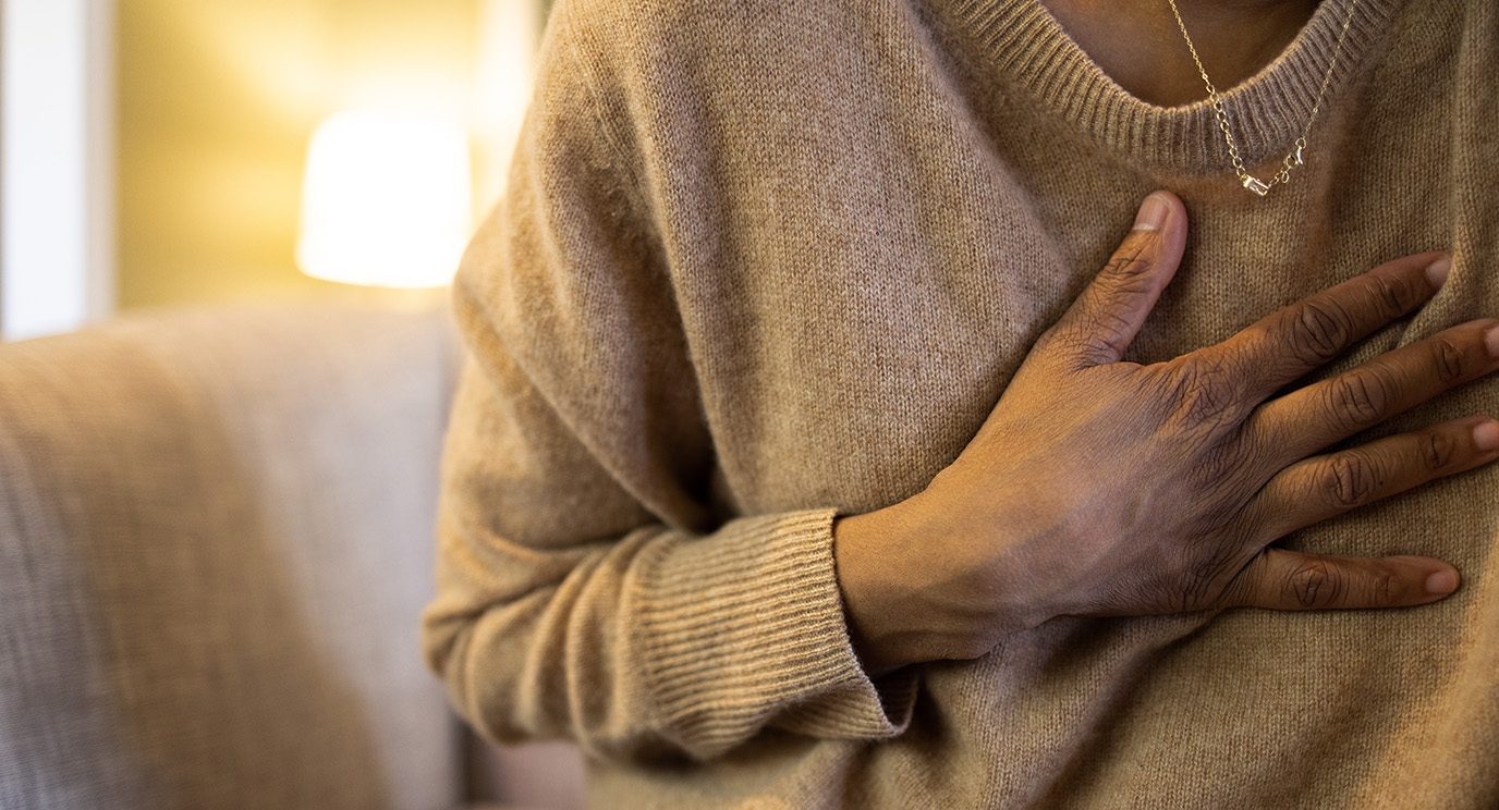 Woman holds her hand to her chest as she experiences chest pain