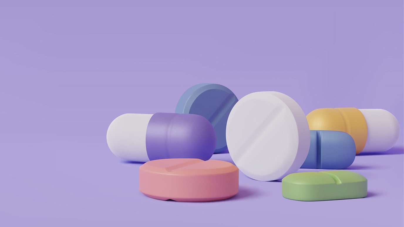 Close-up image of several different types of pills in front of purple background