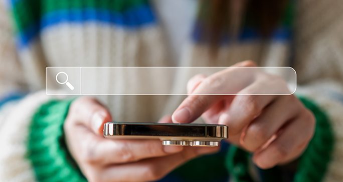 Hands holding a gold phone with an image of a search bar overlaying the image.