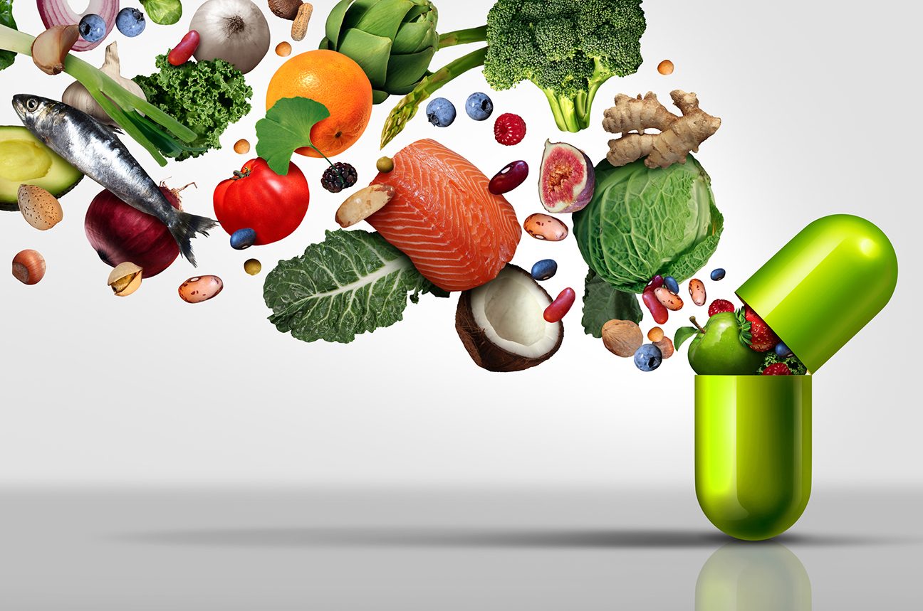 Healthy foods like salmon, coconut, cabbage, and berries emerge from a green pill capsule that's being opened