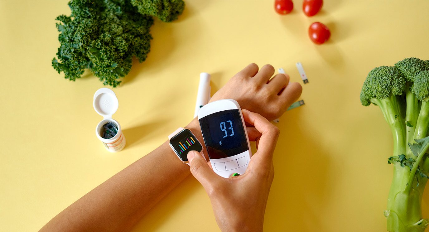 Person uses a glucose meter to check their blood sugar while wearing a smartwatch