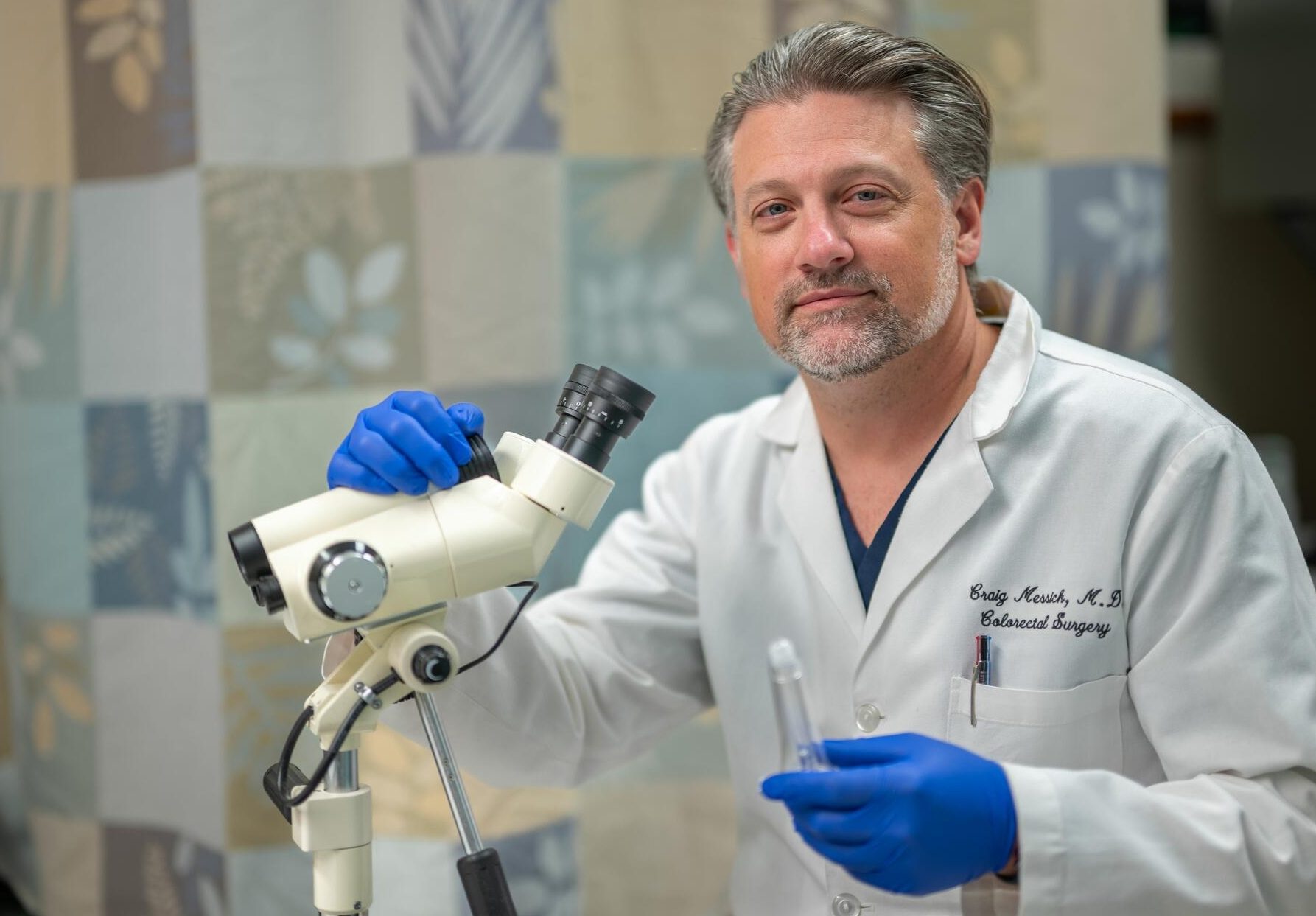 Dr. Messick in clinic wearing blue gloves and holding an anoscope