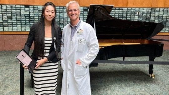 Drs. Mei Rui and Frederick Lang standing next to a piano.