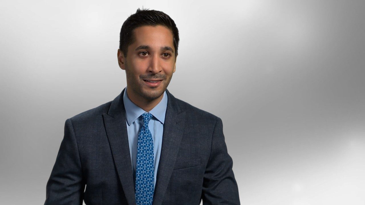 Eric Singhi seated in front of gray background